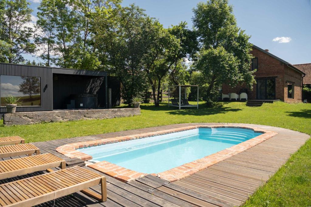 a swimming pool in a yard with a wooden deck at Płowce 7 - Mazurski dom z basenem i SPA in Płowce