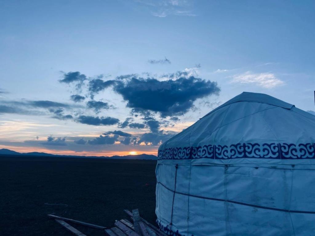 a blue dome tent with the sunset in the background at Sonkol-resort in Song-Kul