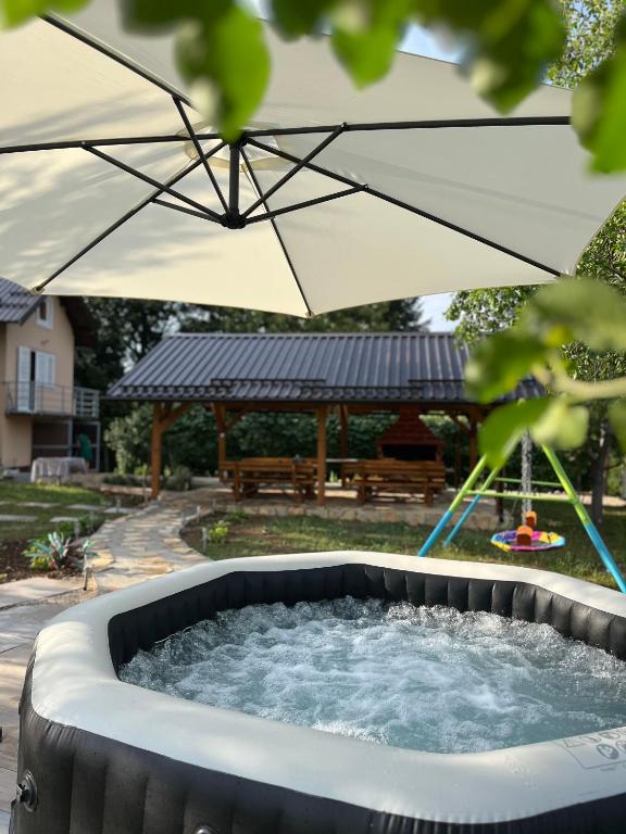 ein Whirlpool mit Sonnenschirm im Garten in der Unterkunft Dva Bora Holiday Home in Banja Luka