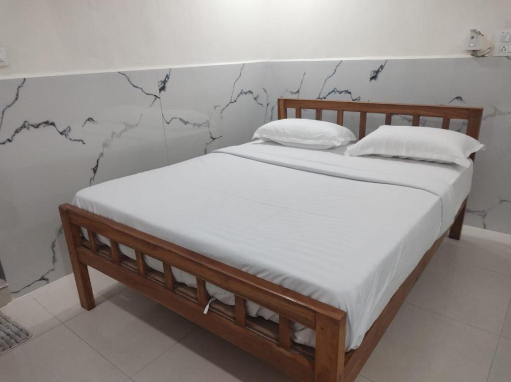 a bed with white sheets and pillows in a room at Wayan Luxury Rooms in Hyderabad