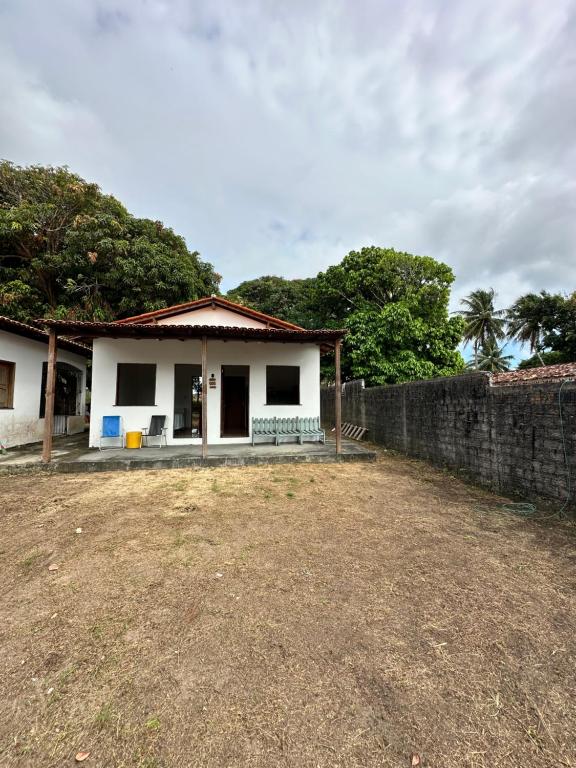 a small white house with a stone wall at Nosso Chalé in Marapanim