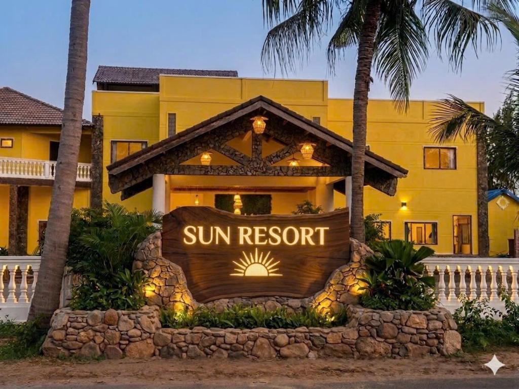 a sun resort sign in front of a yellow building at Sun resort & villa beach in Tiến Thành