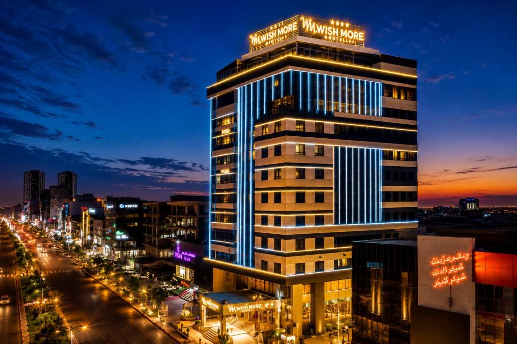 a building with a sign on top of it at night at Wish More Hotel Erbil in Erbil