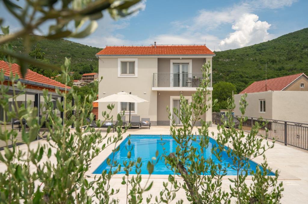 a villa with a swimming pool in front of a house at Villa Sky Stone, Heated Pool, Playground in Krstatice