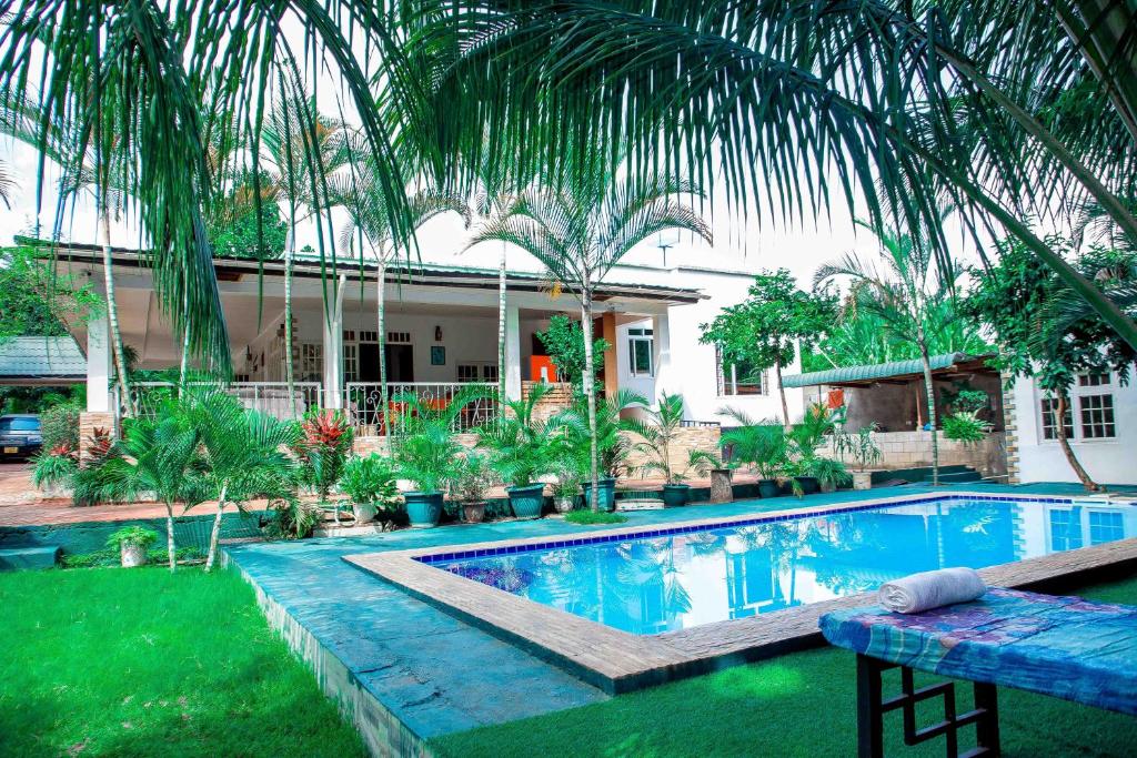 a swimming pool in front of a house with palm trees at Kindo Kicha Farmhouse in Moshi