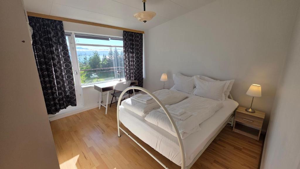 a bedroom with a bed and a desk and a window at Húsavík Apartment in Húsavík
