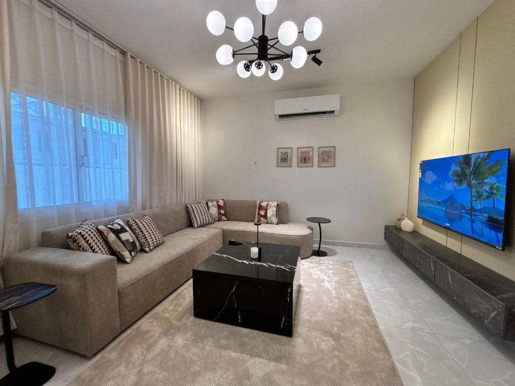 a living room with a couch and a flat screen tv at Bloom Home in Al Khobar