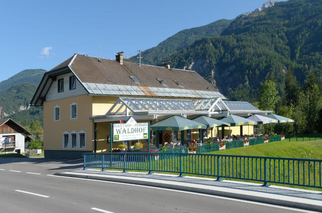 um edifício ao lado de uma estrada ao lado de uma montanha em Gasthof Waldhof em Dellach im Drautal