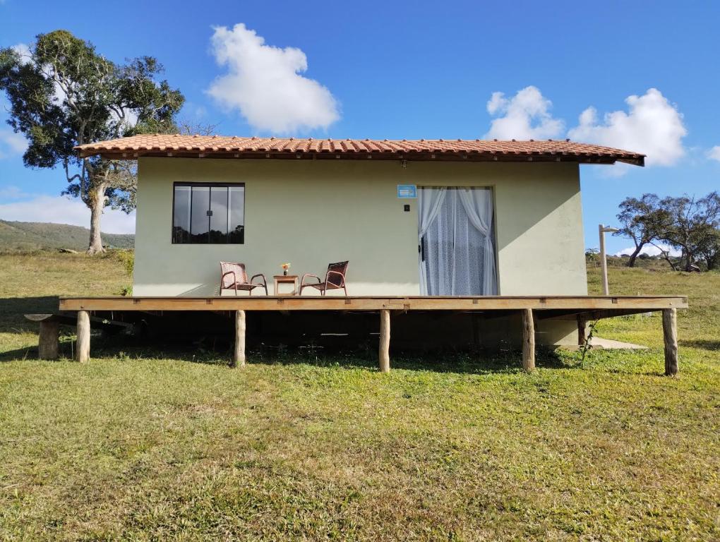 a small house with two chairs on a wooden platform at Chalé Amanhecer in Aiuruoca