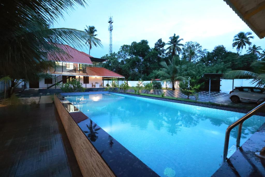 a large swimming pool in front of a house at MeadowView Cottage Marari in Mararikulam