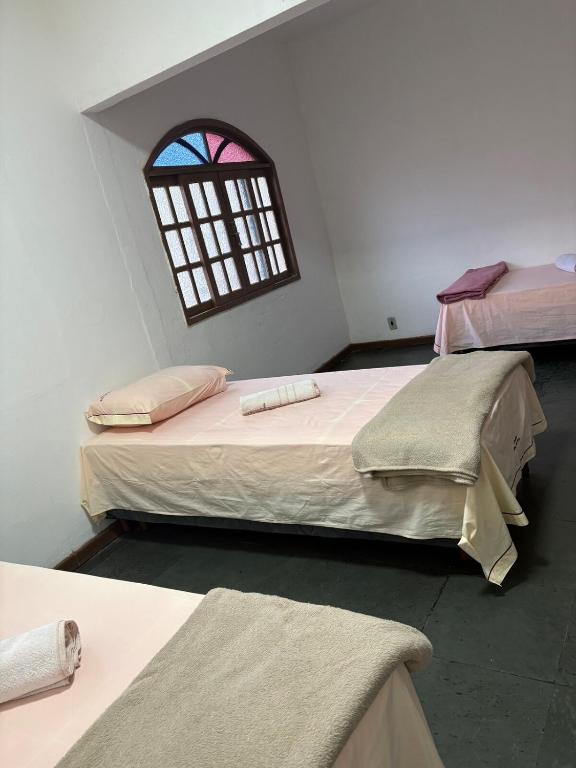 two beds in a room with a window at Excelente apartamento espaçoso com terraço in Macaé