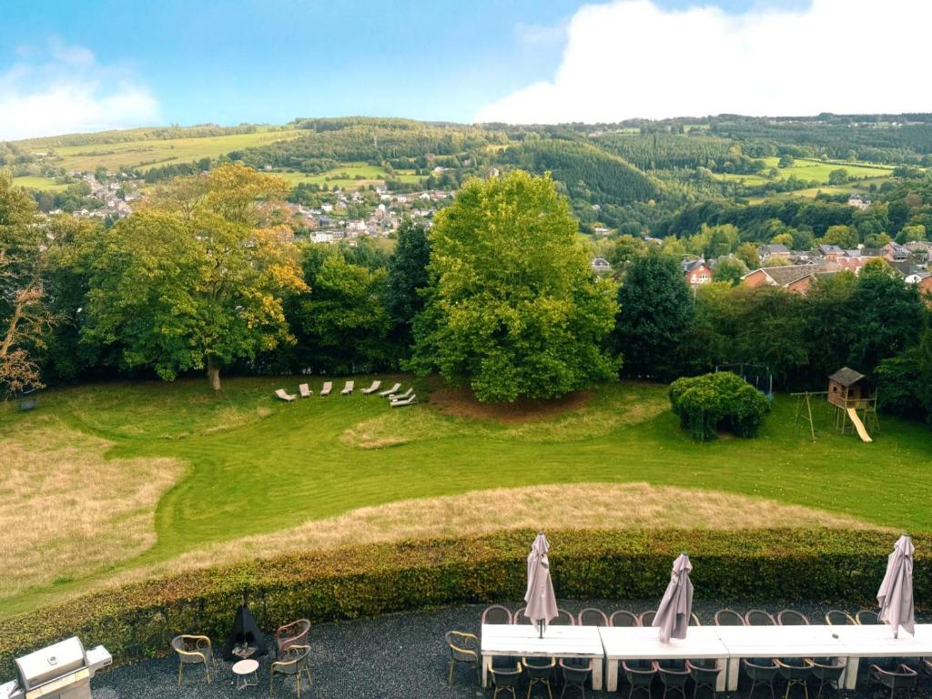 a view of a green field with tables and chairs at Manoir Borzeux in Stavelot
