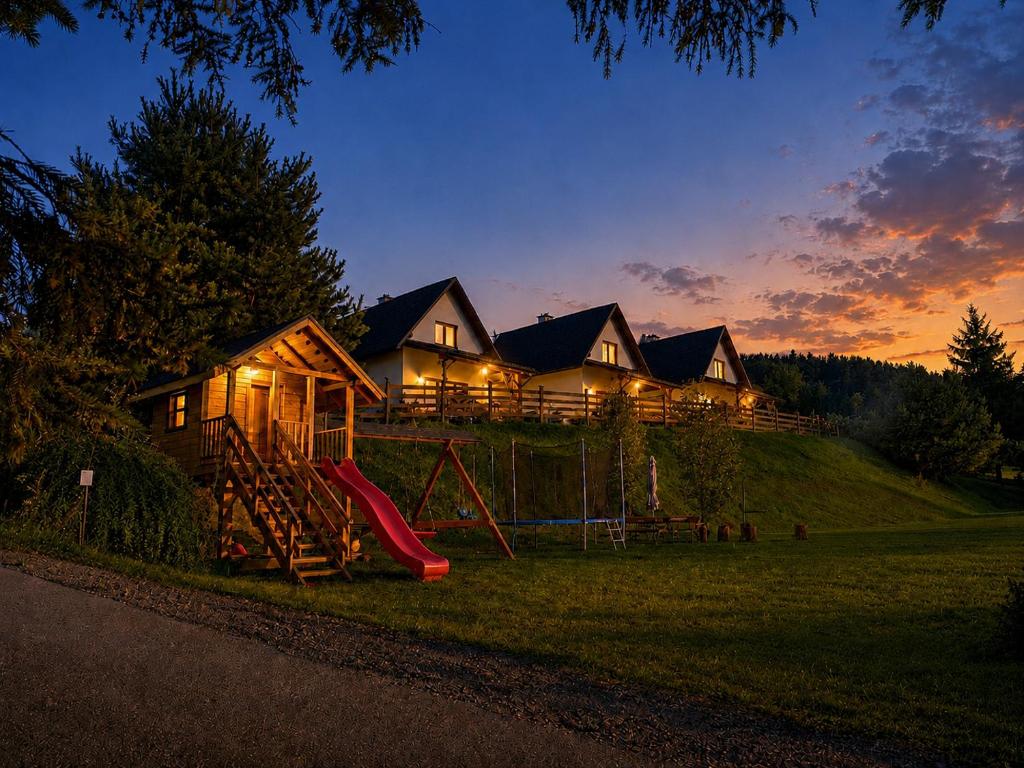 a house with a playground in the yard at night at Bieszczadzki Bohater Domki 533-502-137 in Polańczyk