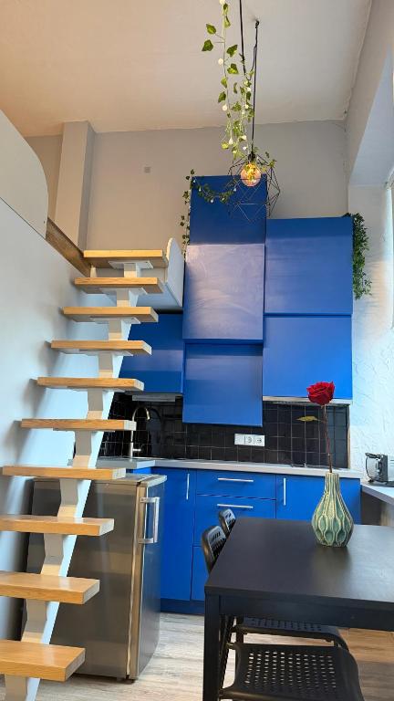 a staircase in a kitchen with blue cabinets at Cozy Loft Studio, one open space, in great location in Vilnius