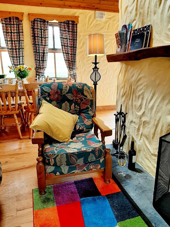 a living room with a chair and a colorful rug at Fanore Holiday Cottages in Ballyvaughan