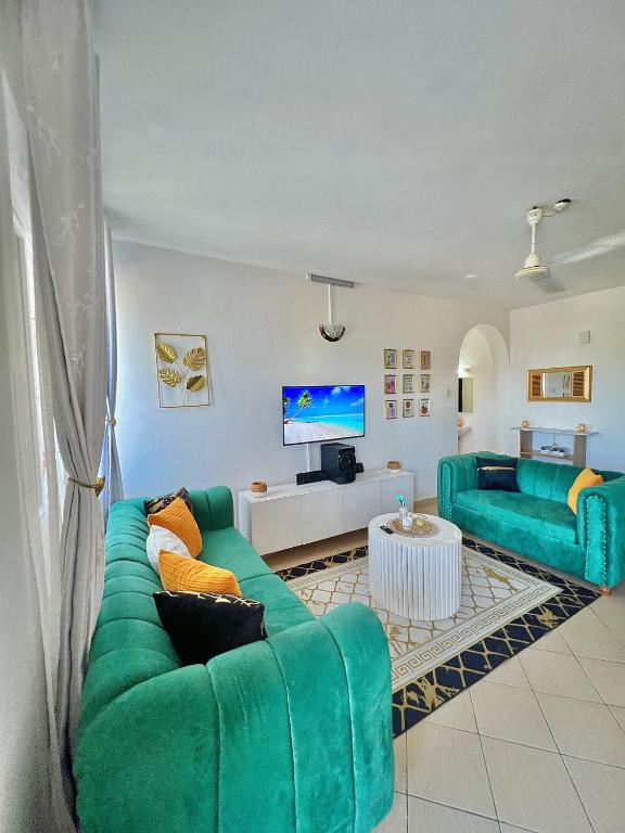 a living room with two green couches and a tv at tabby stays one bedroom with two beds bamburi in Mombasa