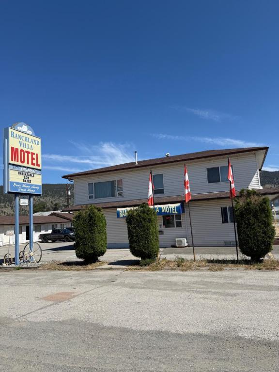 a motel sign in front of a building with flags at Ranchland Villa Motel in Merritt