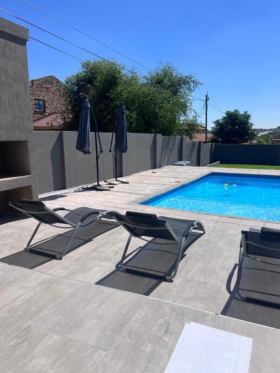 two chairs and umbrellas next to a swimming pool at Zahari Villas in Parys