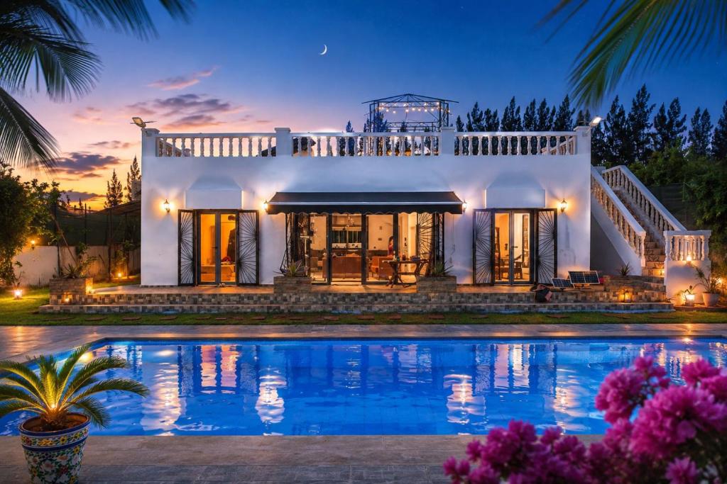 a large white house with a swimming pool at night at Villa Aronora in Rabat