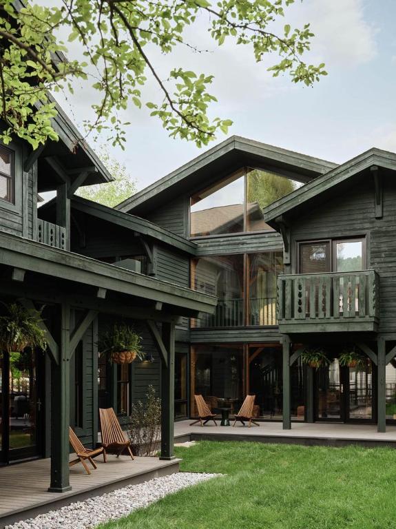 a large wooden house with a balcony and chairs at The Alpine House in Jackson