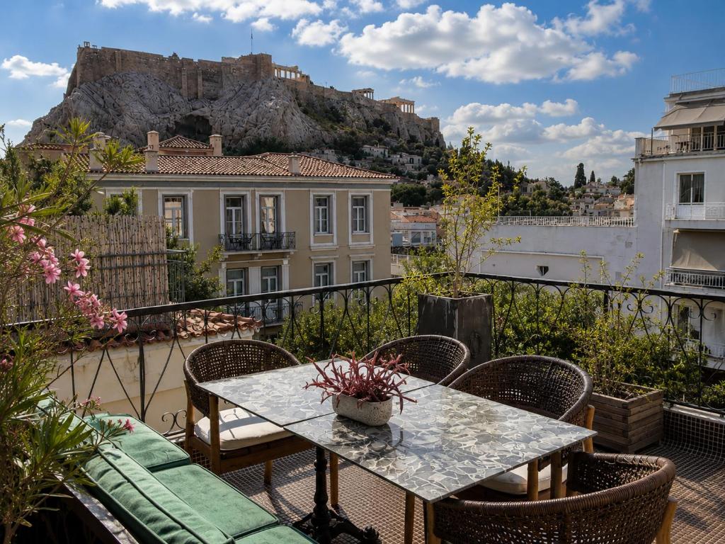 a table and chairs on a balcony with a mountain at ROH Suites in Athens