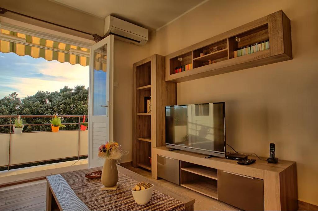 a living room with a television and a large window at Apartment Hotteamo in Silba