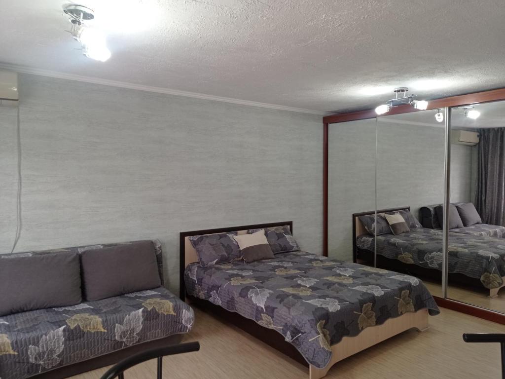 a bedroom with a bed and a couch and a mirror at Уютная 1 комнатная квартира на Сейфуллина 21 in Balqash