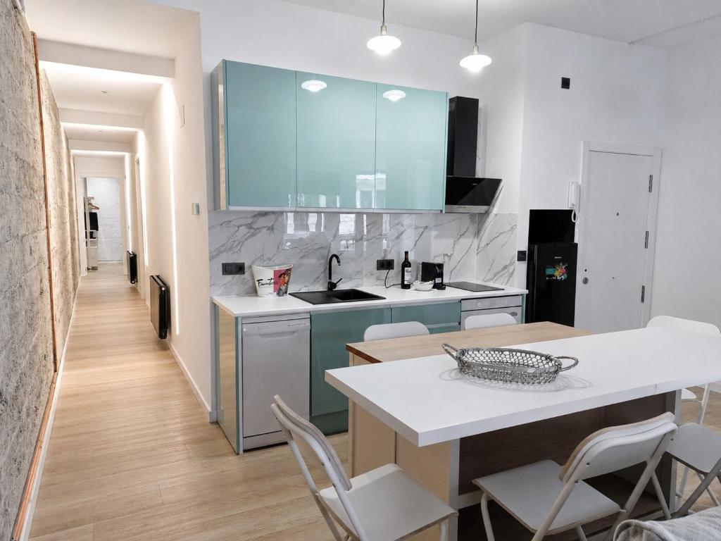 a kitchen with blue cabinets and a table and chairs at MBE Bilbao Centro, 3Hab, 2 Baños, jacuzzi in Bilbao