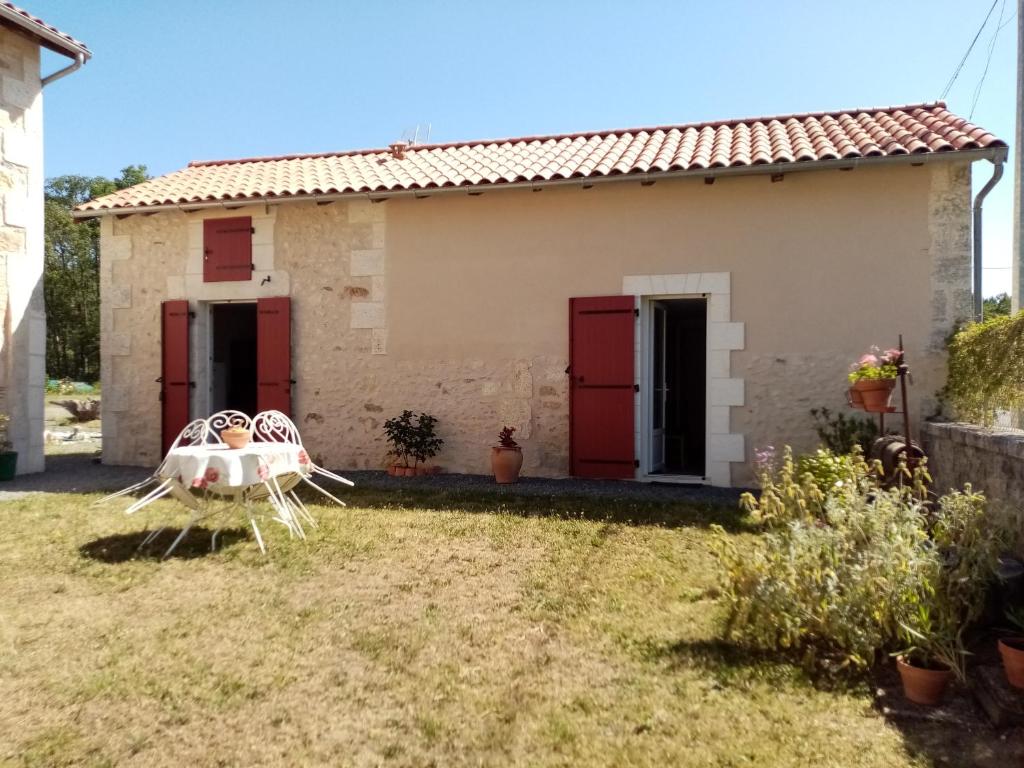 a house with red doors and a table and chairs at petite maison Bellevue in La Celle-sous-Gouzon