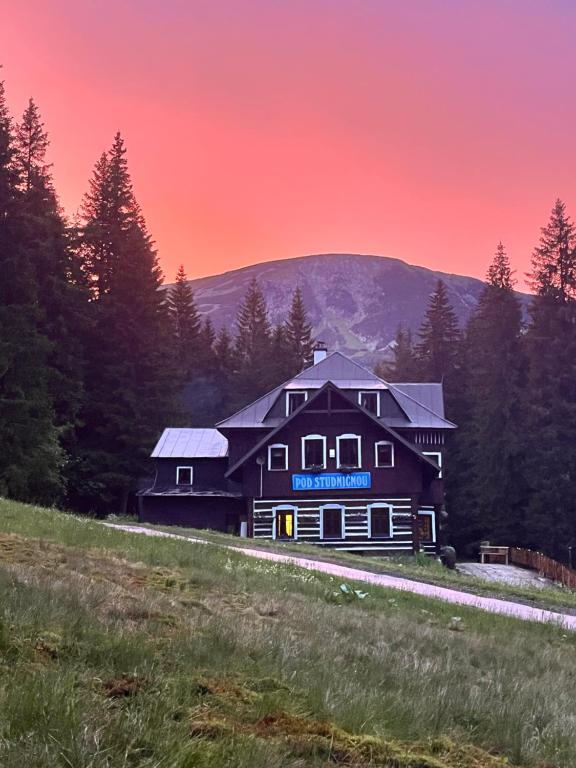 a large house on a hill with a red sky at Chata pod Studničnou in Pec pod Sněžkou