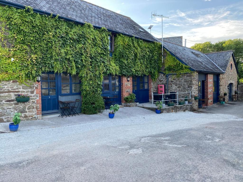 an ivy covered building with blue doors and a table at The Ivy Barn Holbeton in Plymouth