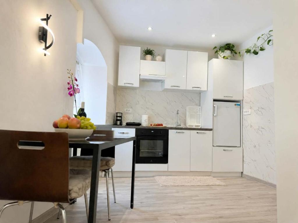 a kitchen with white cabinets and a table with a bowl of fruit at Studio Vesna in Rijeka