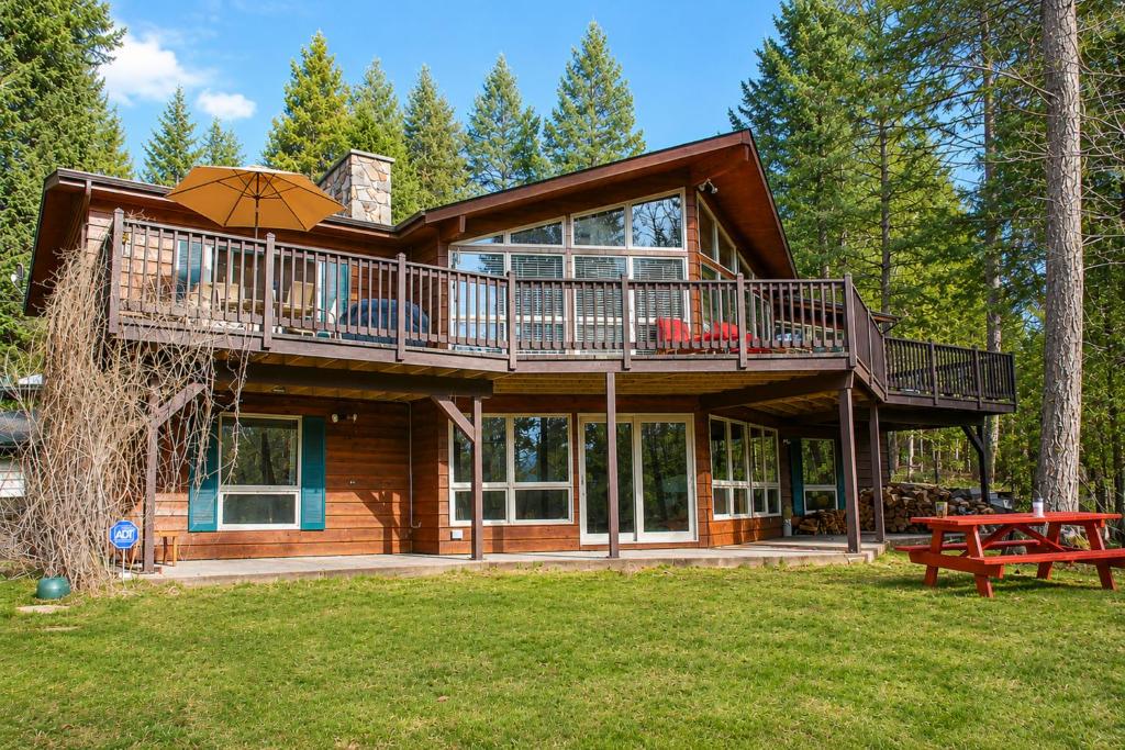 a large wooden house with a balcony and an umbrella at Falcon Cabin in Fairmont Hot Springs