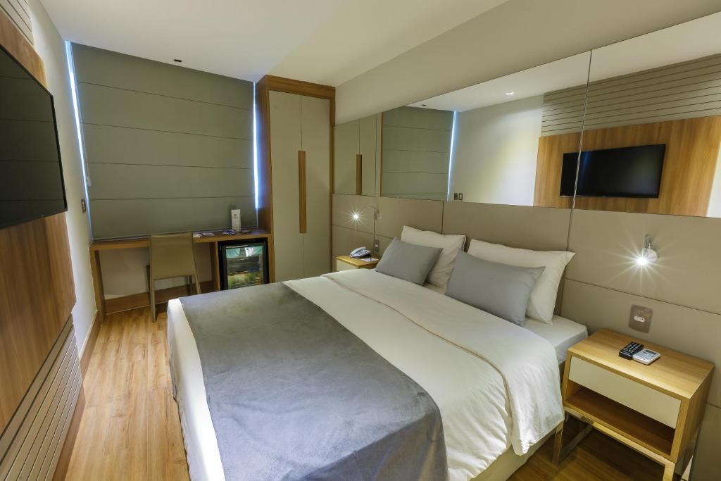 1 dormitorio con 1 cama blanca grande y TV en Hotel Atlântico Travel Copacabana en Río de Janeiro