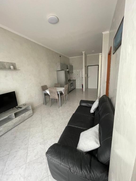 a living room with a black couch and a kitchen at Happy Oasi in Lido Adriano