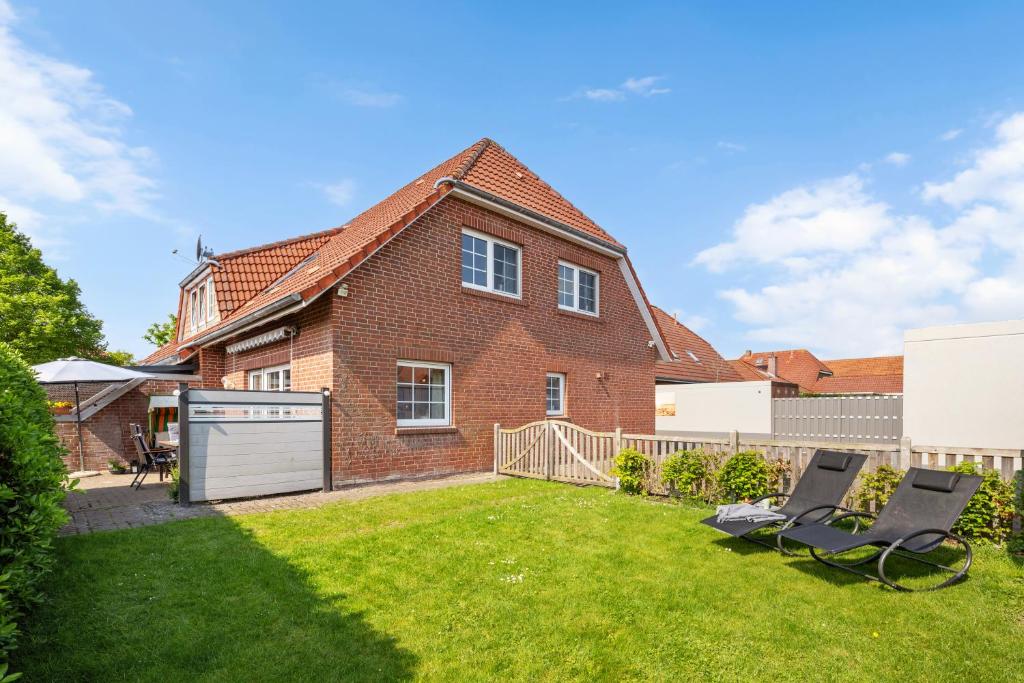 a brick house with two chairs in a yard at Zaunkönigin in Norden