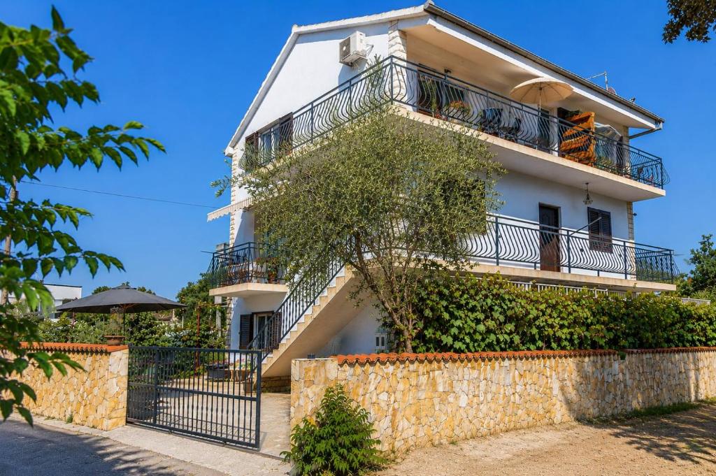 a white building with a fence in front of it at Apartmani Bonaca in Pakoštane