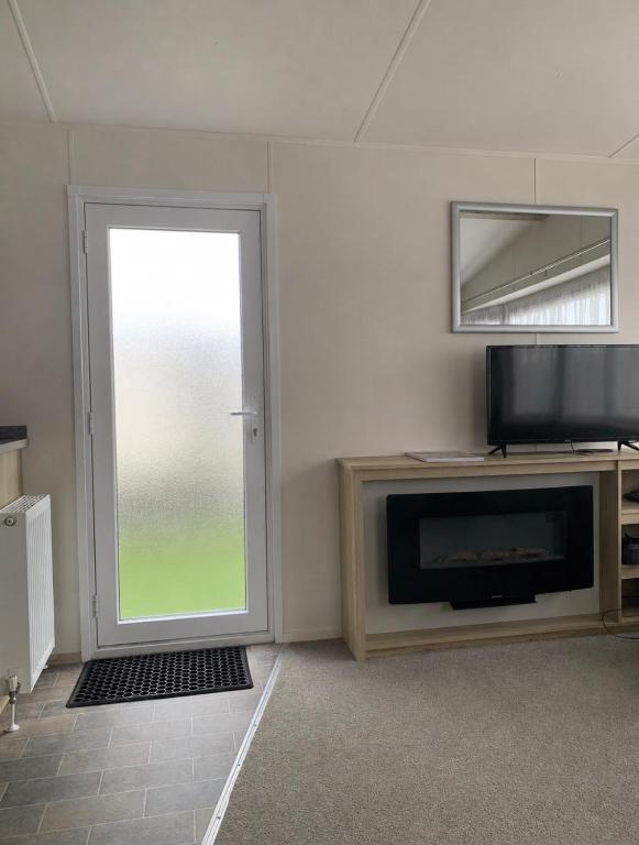 a living room with a television and a window at Seawick Holiday Park in Jaywick Sands