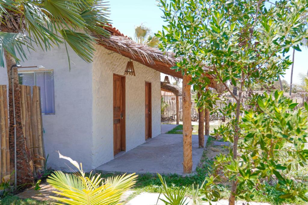 a small white house with a door and some trees at Pousada vila jaguar - arpoador in Tutóia