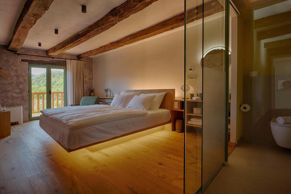 a bedroom with a large bed and a glass wall at Posestvo Pri žabi in Štanjel