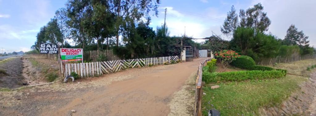 a dirt road with a fence and a sign at DELIGACY RESORT Eldoret in Eldoret