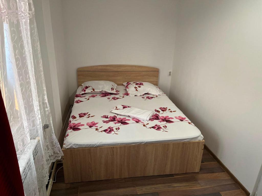 a small bed in a small room with a bedspread with flowers at Pensiunea Florian in Tulcea