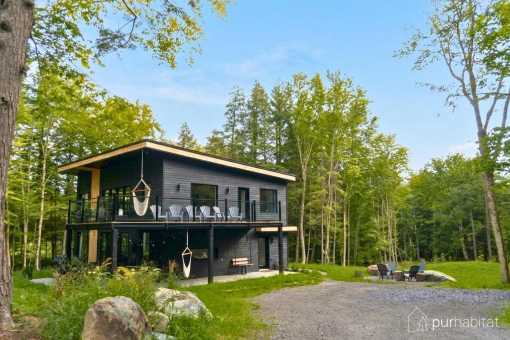 a house with a wrap around deck in the woods at Pur Nature et Spa Owl's Head in Mansonville