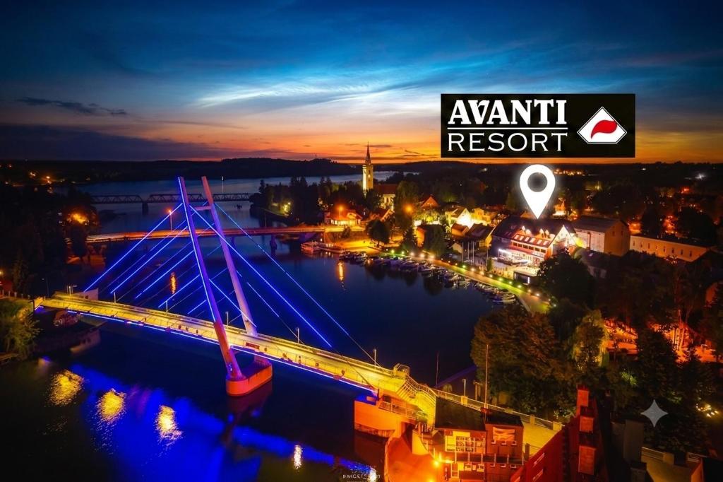 a bridge over a river with a city at night at Avanti Resort Mikołajki , w centrum przy jeziorze i promenadzie, śniadanie , obiad lub obiadokolacja in Mikołajki
