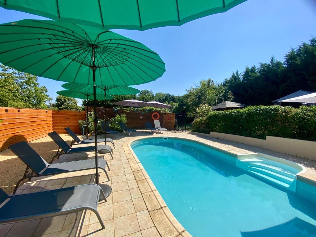 a swimming pool with chairs and a green umbrella at Domaine Ô Clair de Lune - Chambres d'Hôtes et Gîtes à Sarlat - Accès Cité Médiévale 5 minutes à pied - Parking - SPA & Massages en option - Piscine de saison in Sarlat-la-Canéda