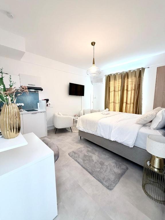a white bedroom with a bed and a tv at Cocon doré au coeur de Limay in Limay