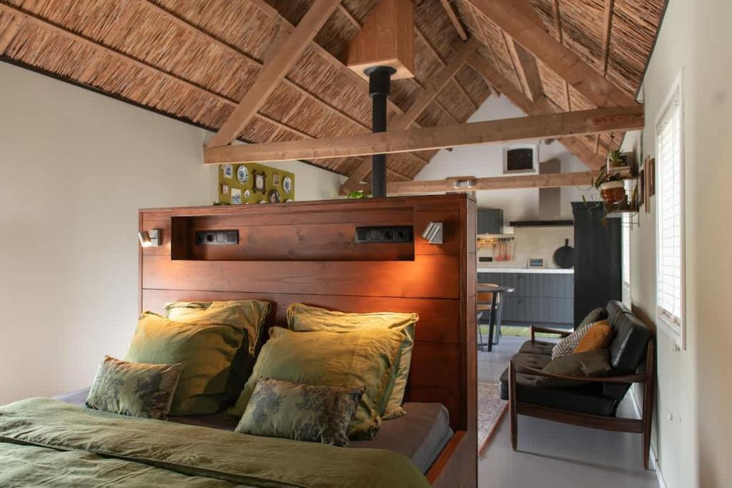 a bed with a wooden headboard in a room at Gastenverblijf Begheynhof - your perfect escape in Biervliet