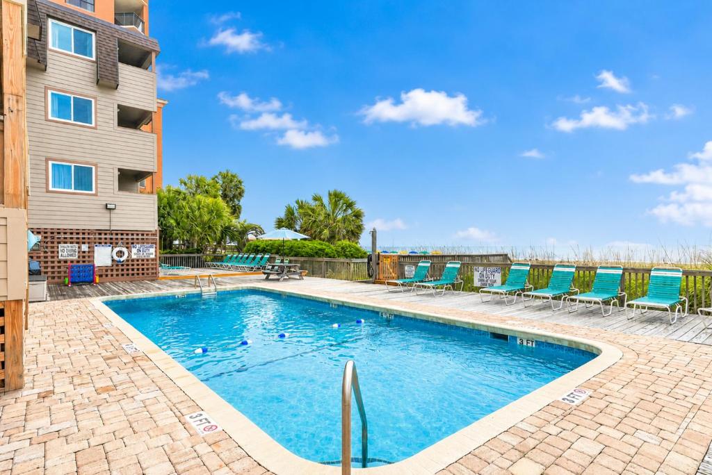 a swimming pool with chairs next to a building at Ocean Forest Colony in Myrtle Beach