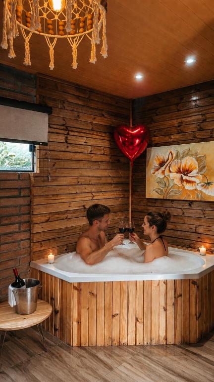 two people in a bath tub with a heart at Chalés Manacá dos Canyons in Praia Grande