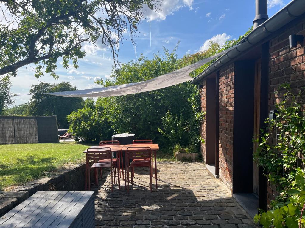 eine Terrasse mit Tisch und Stühlen unter einem Sonnensegel in der Unterkunft Bayda's Tiny House in Sprimont